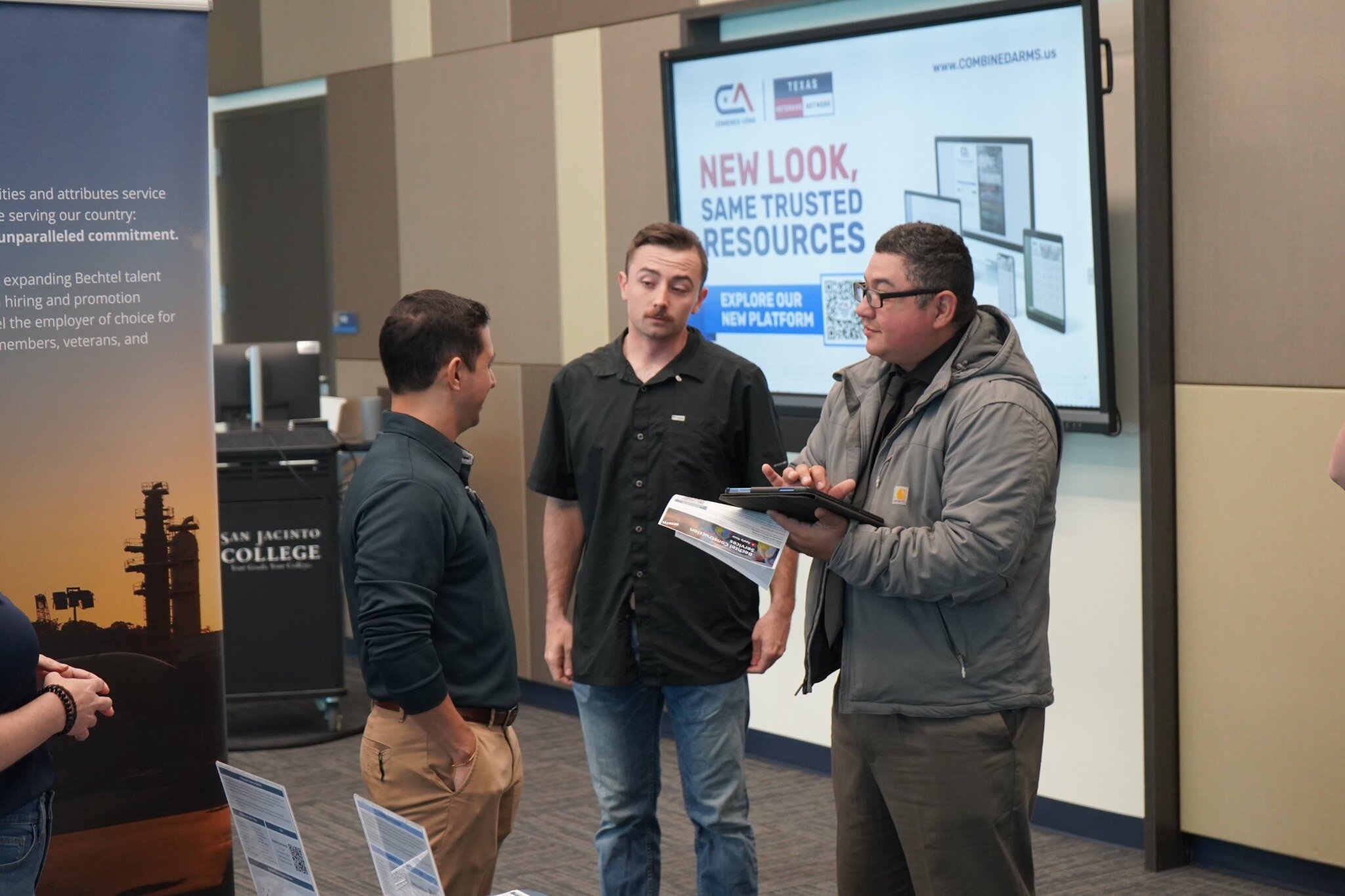 veterans talking and holding computer at event